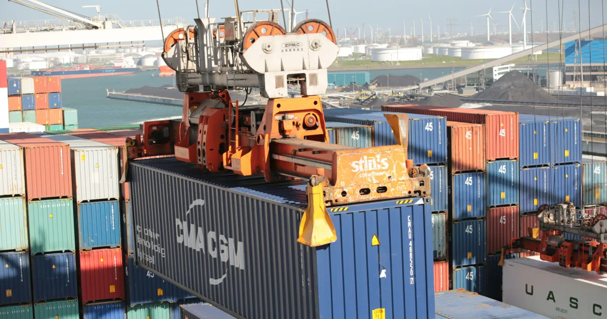 Conteneur maritime soulevé par un portique sur un terminal portuaire, prêt pour l'expédition vers les Comores
